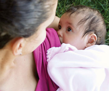 Woman breastfeeding baby and looking down at the baby.