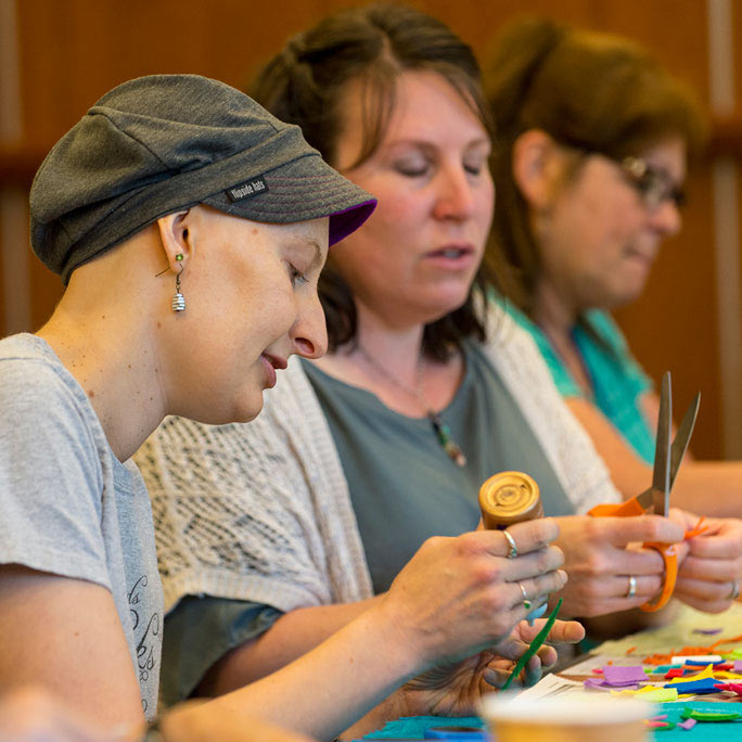 Three people working with scissors, glue, and felt.