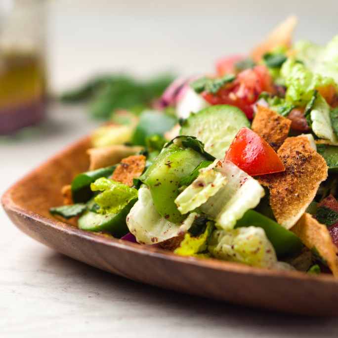 Chopped salad on a wooden plate.