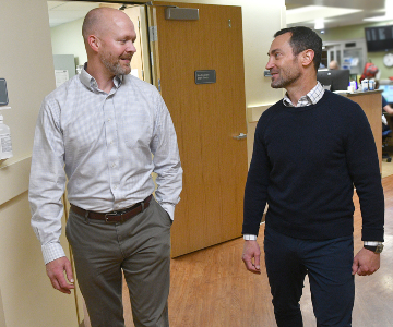 Two men involved with the program to prevent kidney injuries, walk through a Good Sam corridor.
