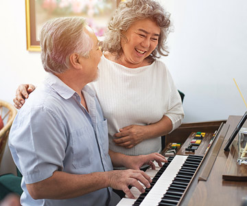 Older couple sitting at a piano enjoying music together.