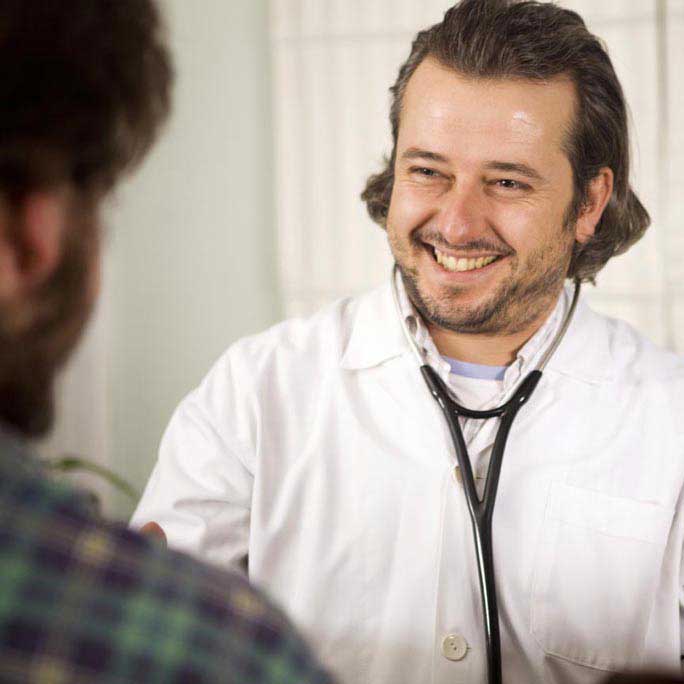Male doctor smiling at male patient.