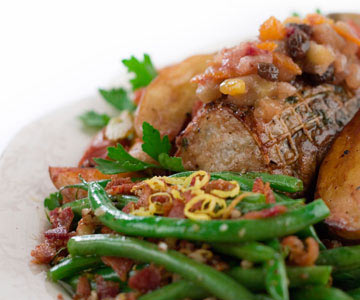 Green beans alongside a beef entre with chutney on a white dinner plate.