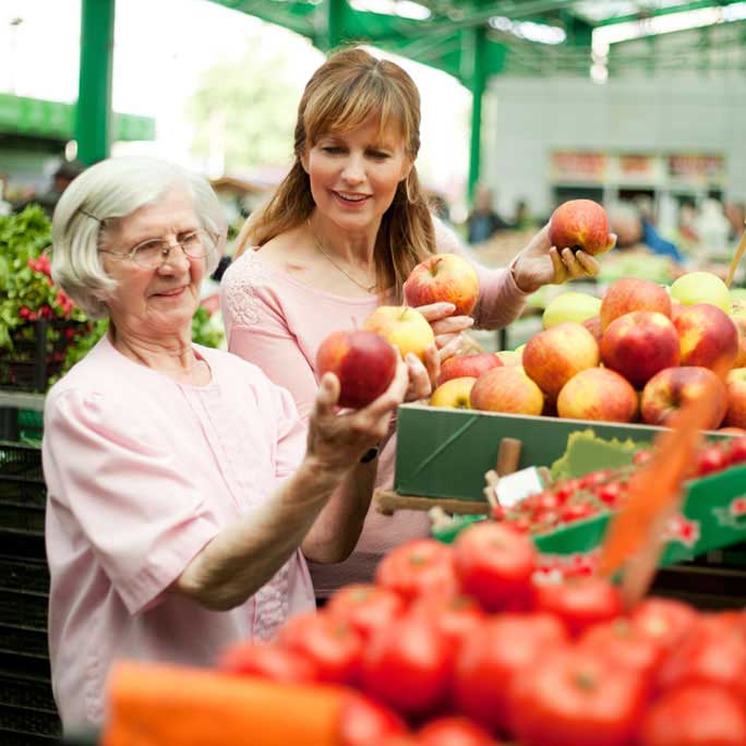 Women look at apples at farmers market