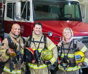 Three firefighters in front of fire truck.