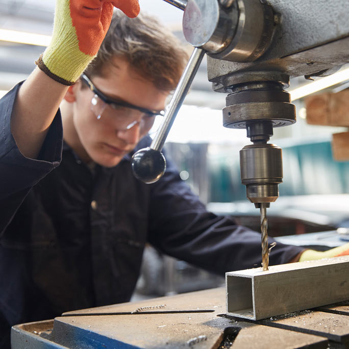 Drill press operator focused on drilling.