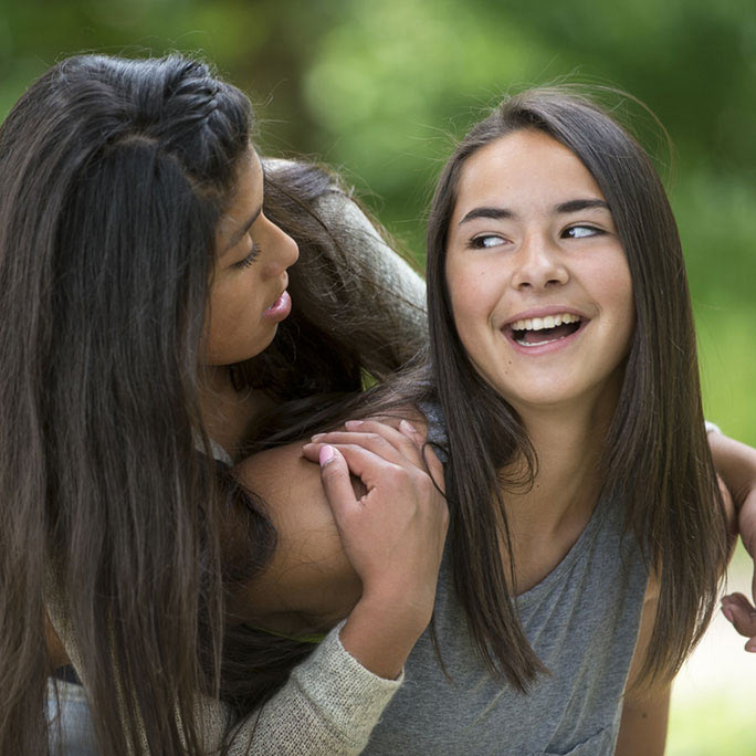 Two friends smiling at eachother.