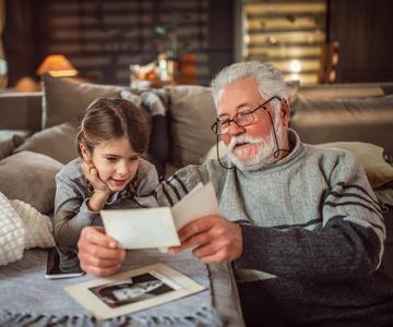 Grandad showing his granddaughter memories from photos.