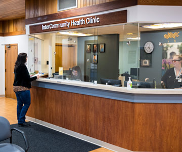 A woman stands at the reception window of the InterCommunity Health Clinic in Albany, Oregon.