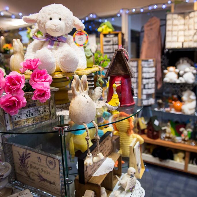 Gift shop display with stuffed animal lamb and other small items.