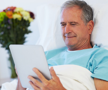 Man in hospital bed with tablet in hands