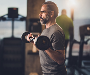 Man lifting free weights in a gym.