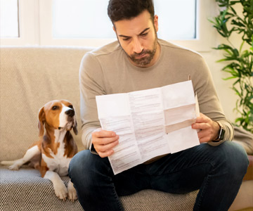 Man sitting on couch reading with his dog beside him.