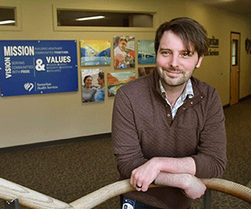 Health plans program manager standing, smiling near staircase