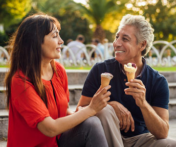 A middle-aged couple enjoys ice cream cones on a date.