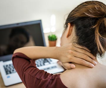 Person holding the back of their neck in pain.