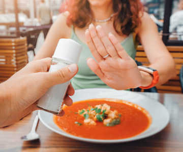 Person holding up their hand and refusing the salt shaker.