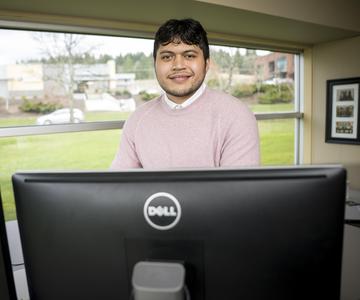 Noah Seumalo standing in front of a computer monitor.