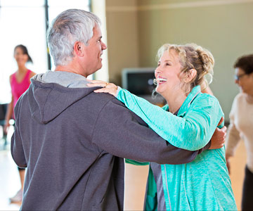 Older couple laughing while attending a dance class.