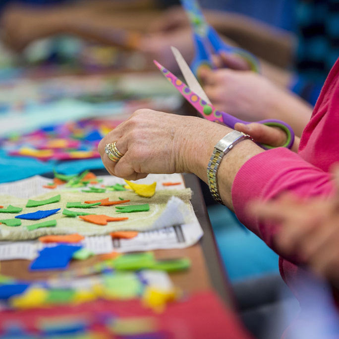 Hands and scissors over pieces of felt.