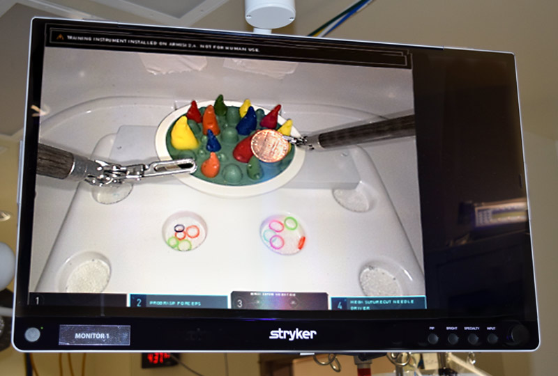 Monitor view of the da Vinci robot picking up a penny.