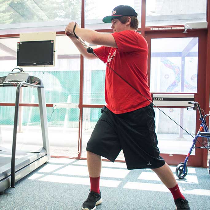 Standing person pulling exercise band across body.