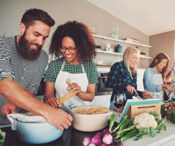 People preparing a healthy plant-based meal in a large kitchen.