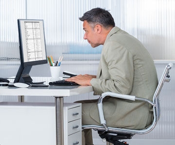 Man slumped at desk in front of computer screen