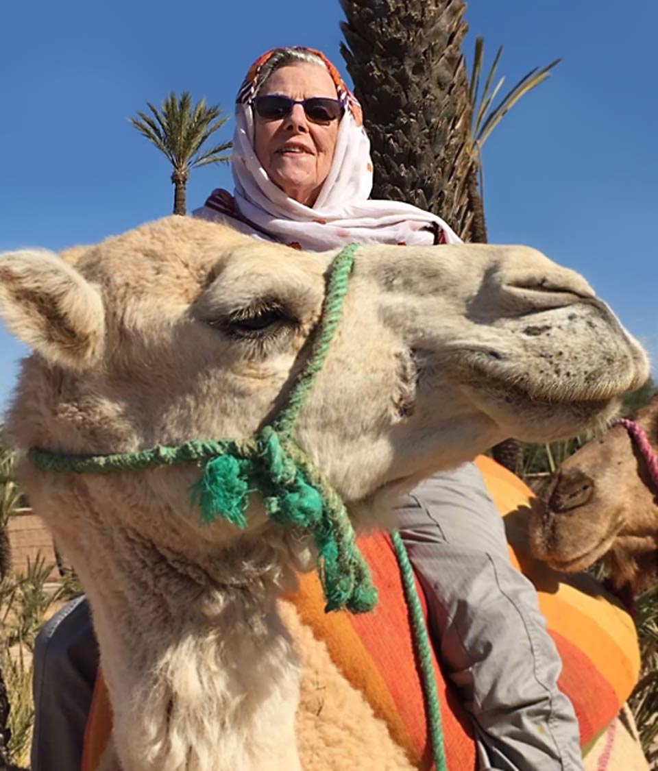 Alice riding a camel while in Morocco volunteering for the Peace Corps.