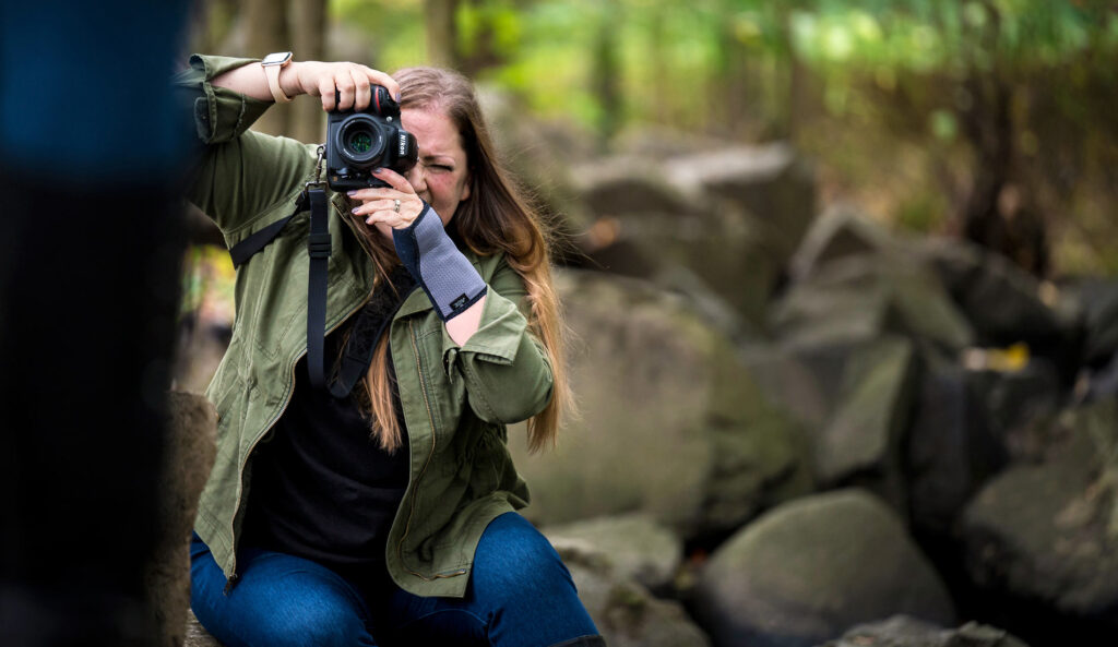 Ashley squatting down to get the right angle as she takes a picture of her subject at a local park.