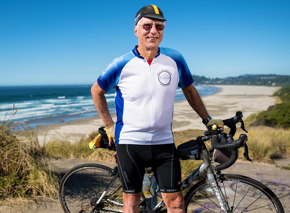 Conrad, smiling, standing with his bike above Nye Beach in Newport, Oregon.