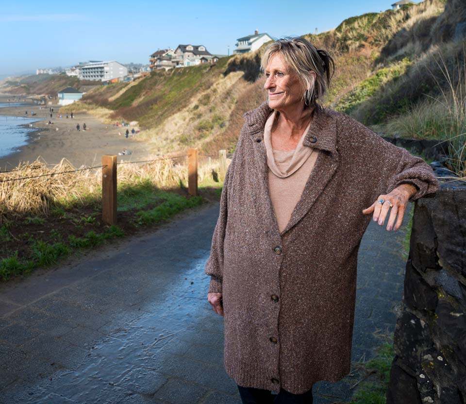 Cyndee smiling as she looks down at Nye Beach from the walkway above.