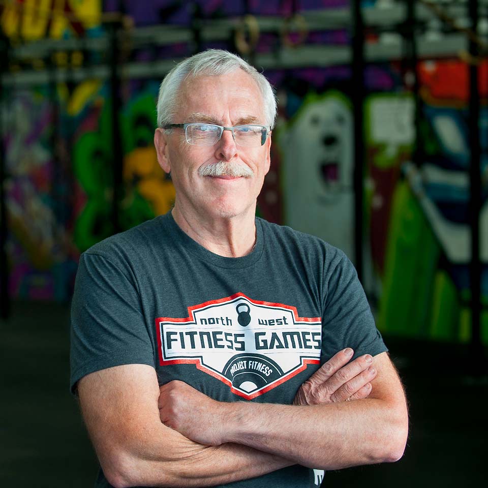 A confident Gary smiling at the camera with his arms crossed in front of him.