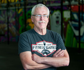 A confident Gary smiling at the camera with his arms crossed in front of him.