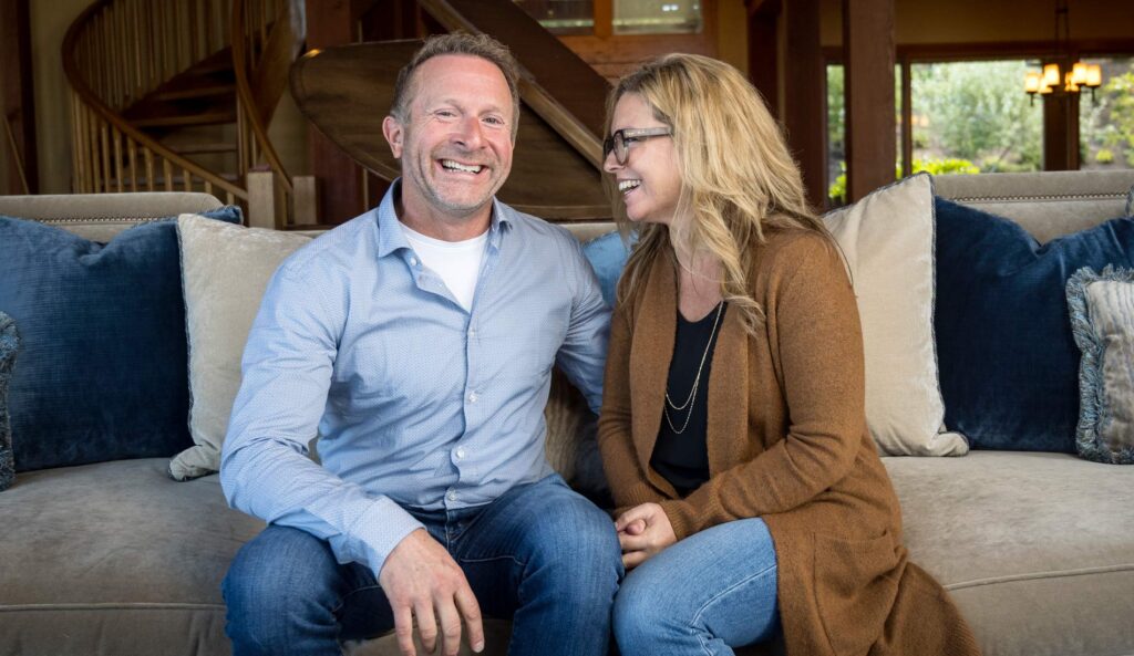 Kent and his wife sharing a laugh as they sit on a couch in their home.