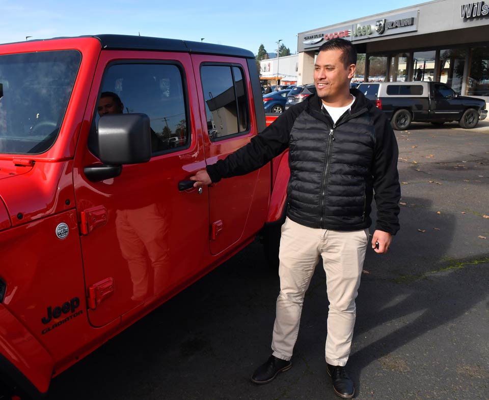 Mike standing next to a new Jeep at his workplace.