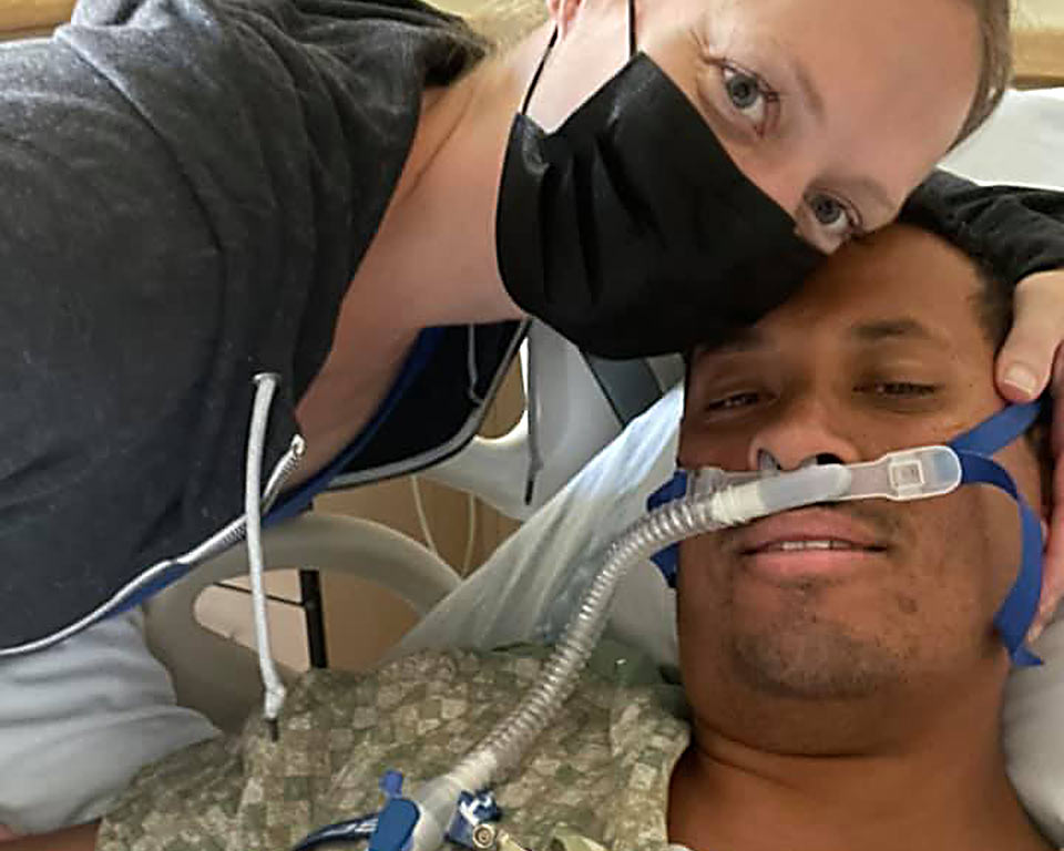 Close up of Mike and his wife as she leans over him in his hospital bed.