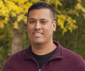 Close up of Mike smiling with fall leaves behind him.