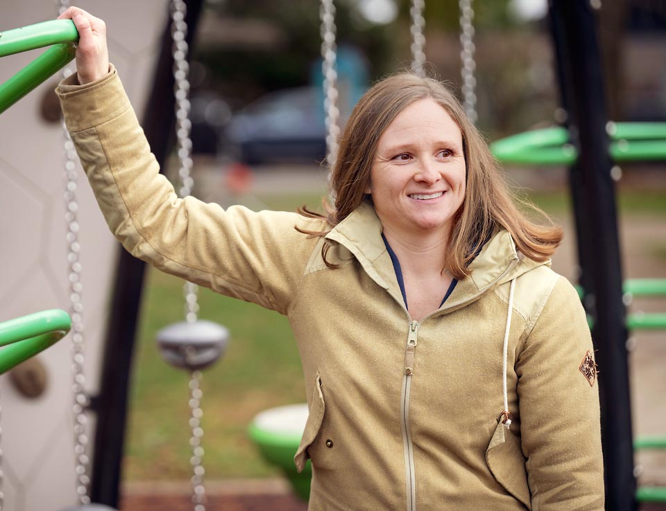Morgan watching her sons play at an outdoor playground structure.