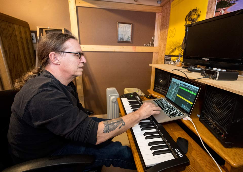 Rik composing in front of his laptop and electronic keyboard.