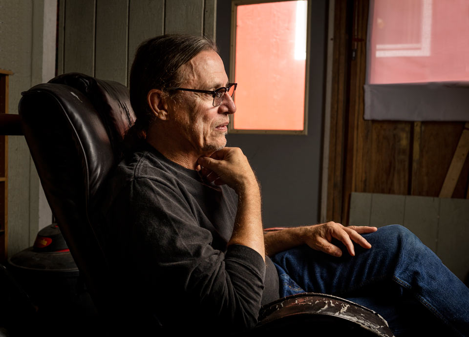 Rik in his home, sitting contemplatively in a comfortable chair.