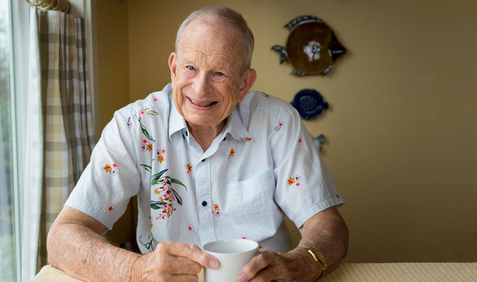 Tom sitting at his kitchen table enjoying a cup of coffee.