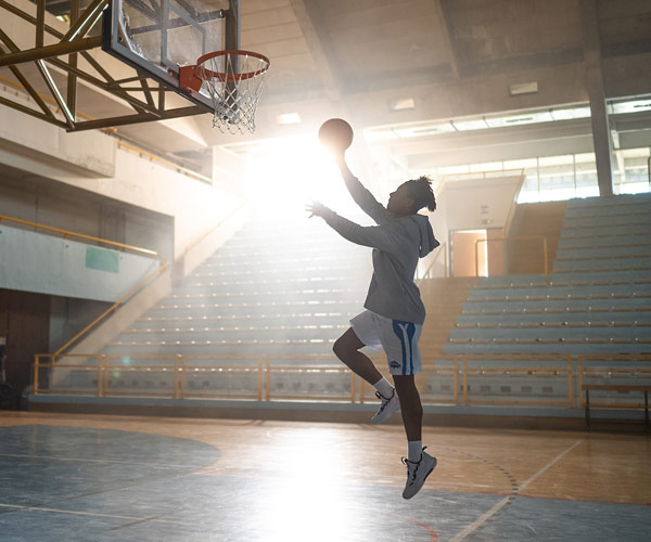 A silhouetted basketball player making a lay up.