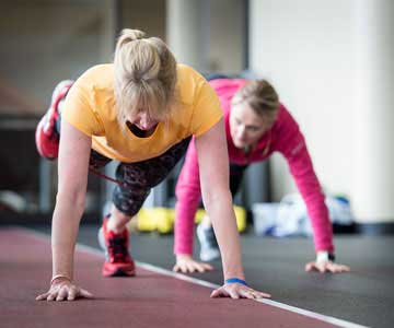 Two women doing stretches on track.