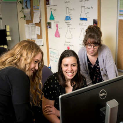 Three smiling women look at a computer in Samaritan research lab.