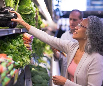 A woman picking out colorful produce at grocery store.