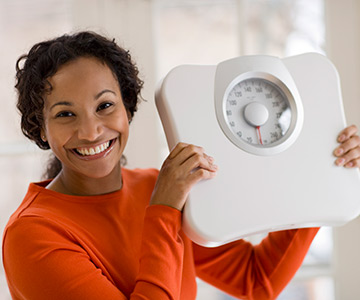 Smiling woman holding scale in triumph.