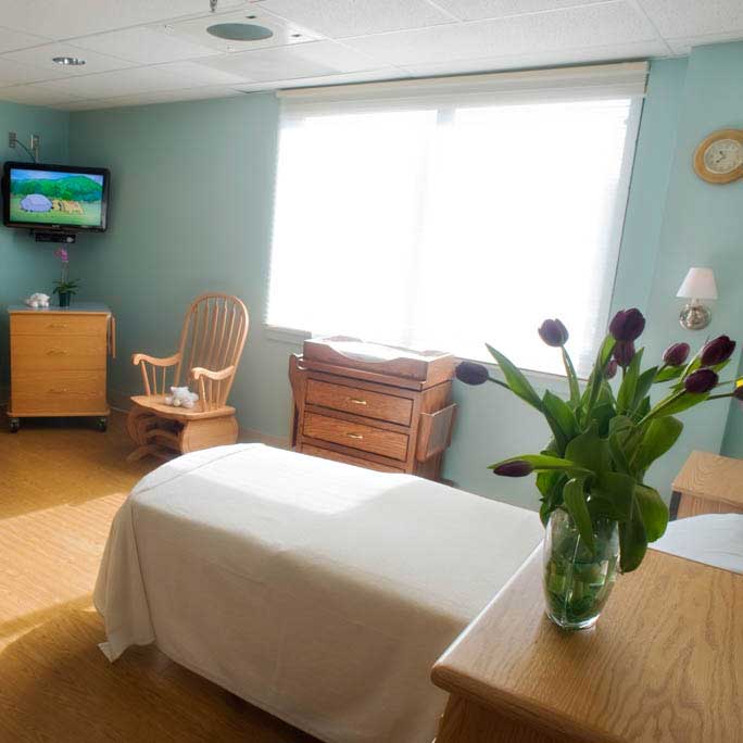Maternity birth room with bed and chair.