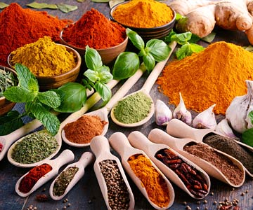 Wooden spoons full of colorful spices and dried herbs.