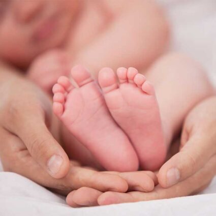 Baby's feet held by hands